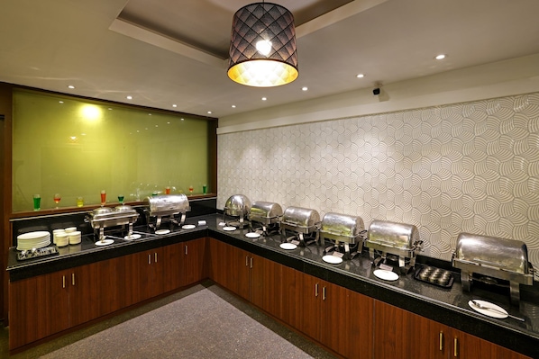 Una cocina de hotel con barra de buffet, varios dispensadores de alimentos y un espejo grande sobre la encimera.