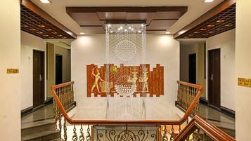 Una escalera con barandillas ornamentales, un muro decorativo con una figura y un aplique colgante.