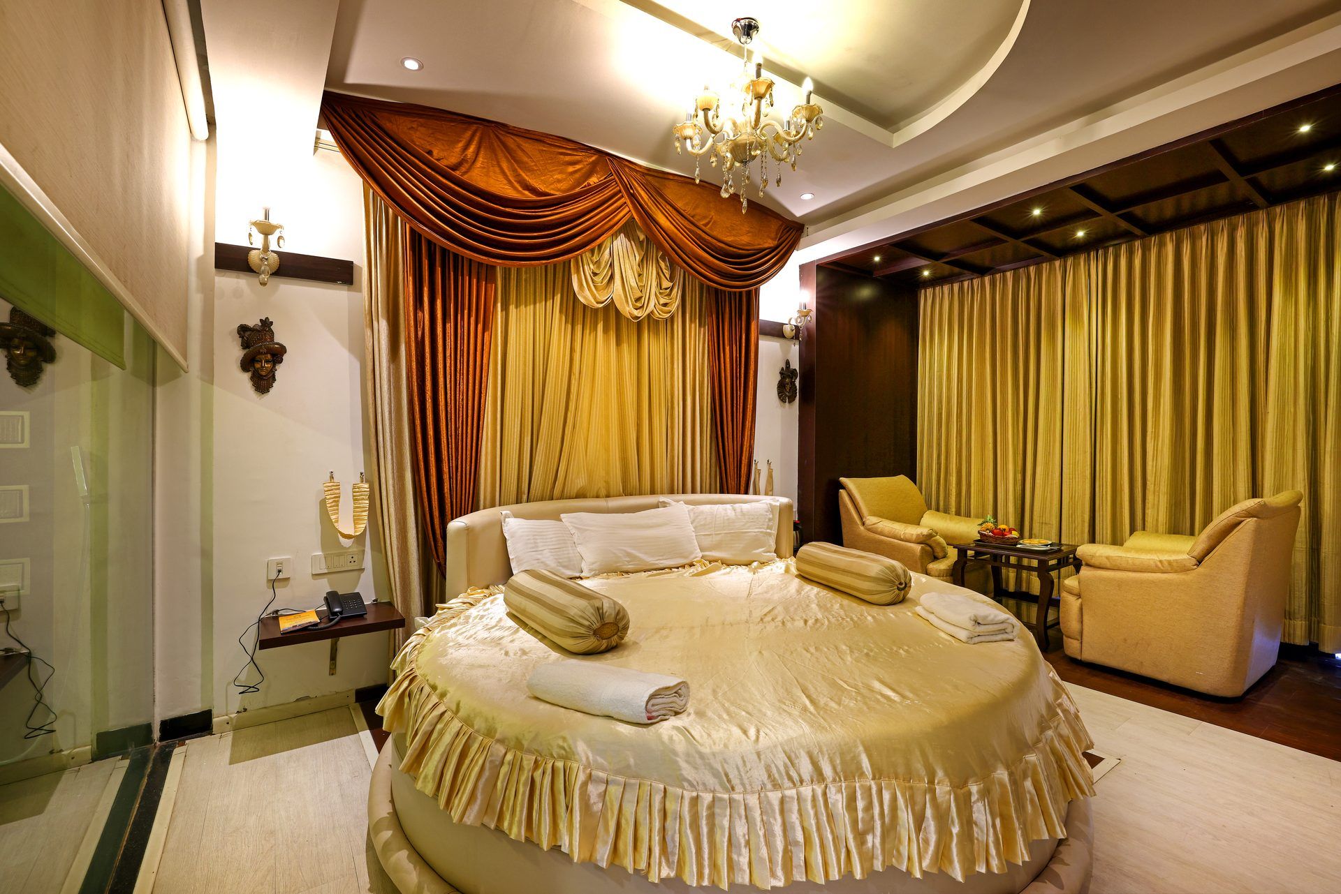 Ein luxuriöses Schlafzimmer mit einem großen Bett, einer Chandelier und einer Sitzecke mit zwei Sesseln und einem kleinen Tisch.