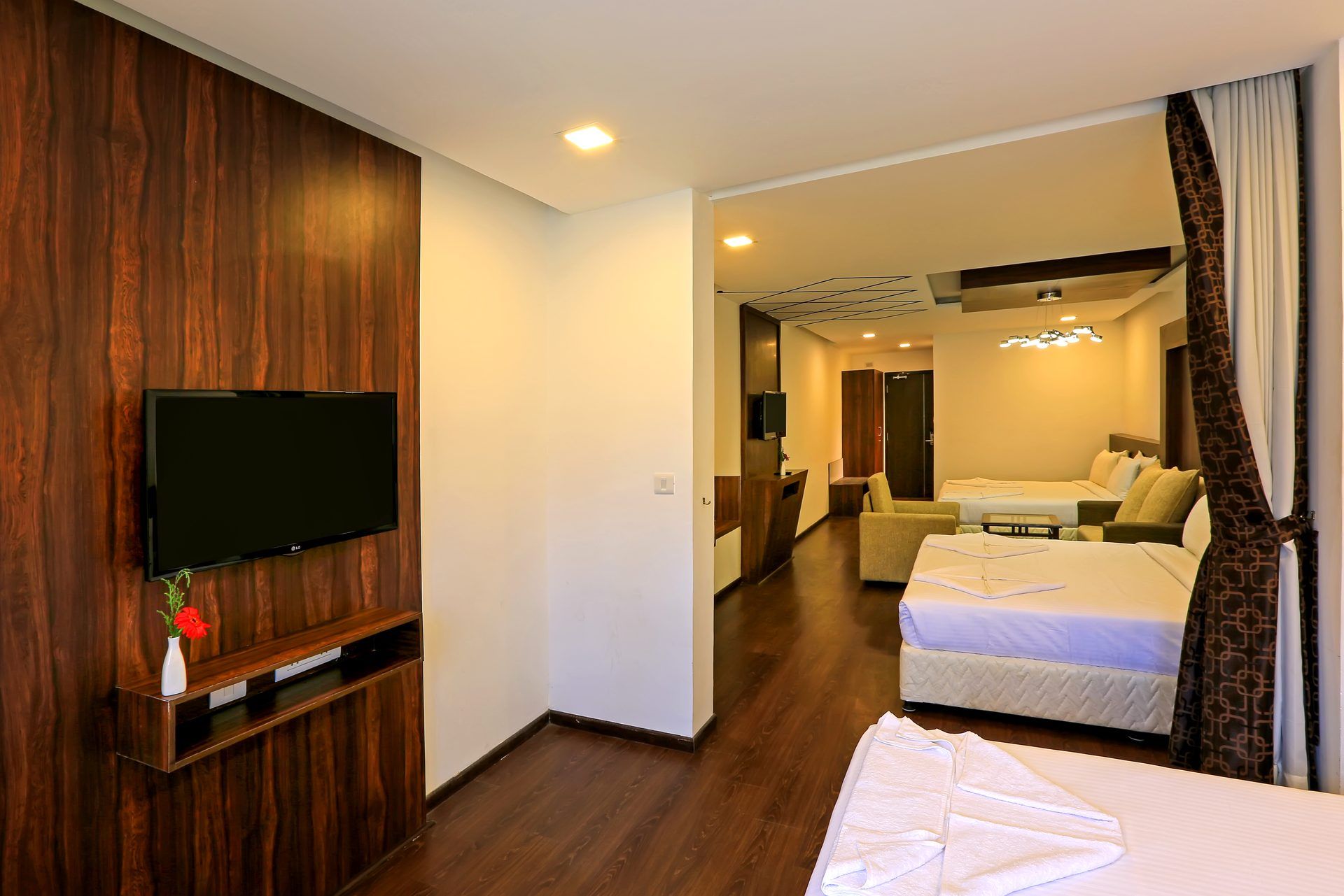 Ein Hotelzimmer mit Flachbildfernseher, einer Wand aus Holzpaneelen, einem Bett mit weißer Bettwäsche, einer Couch und einem kleinen Tisch.