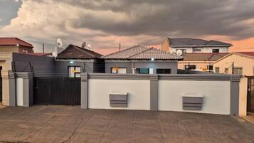 Zona residencial con casas, una entrada vigilada y cielo nublado.