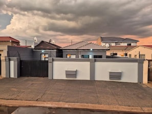 Zona residencial con casas, una entrada vigilada y cielo nublado.