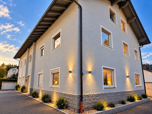 Un immeuble à plusieurs étages, doté d’un toit plat, de nombreuses fenêtres et d’une façade bien éclairée.
