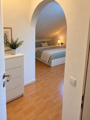 A bedroom with a bed, bedside table, lamp, and a potted plant. - Apartment 'Felix Living 15 – Lusenblick - 2 Schlafzimmer & 2 Bäder' (Mauth)