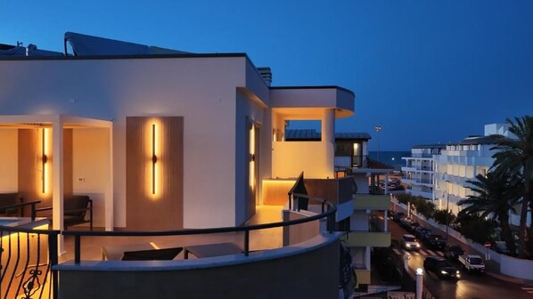 A modern hotel with a balcony, a pool, and a view of the street.