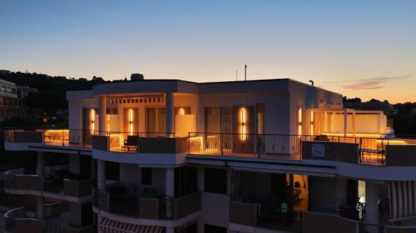 Un edificio de varios pisos con balcones e iluminación exterior.