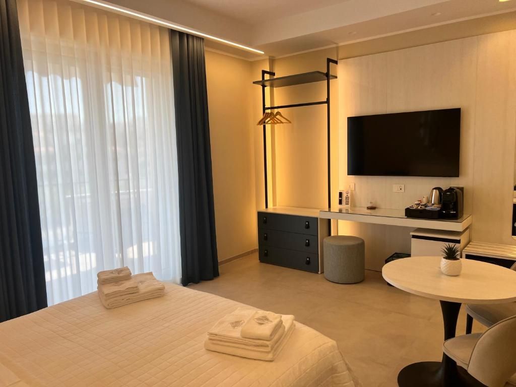 Habitación de hotel con cama, mesita de noche, escritorio con televisor de pantalla plana, perchero y mesa redonda.