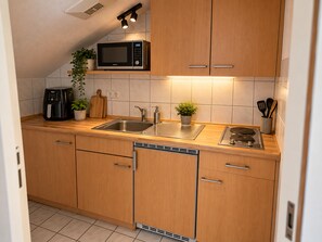A modern kitchen with wooden cabinets, a stainless steel sink, a microwave, and a coffee maker. - Apartment 'Felix Living 16 – Lusenblick' for 2 guests (Mauth)