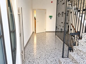 A hallway with a terrazzo floor, a metal gate, and a door with an emergency exit sign. - Apartment 'Felix Living 16 – Lusenblick' for 2 guests (Mauth)