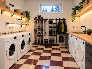 A laundry room with multiple washing machines, a drying rack, and a window with a view of trees. - Apartment 'Felix Living 16 – Lusenblick' for 2 guests (Mauth)