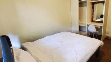 A bedroom with a bed, a chair, a wardrobe, and a mirror.
