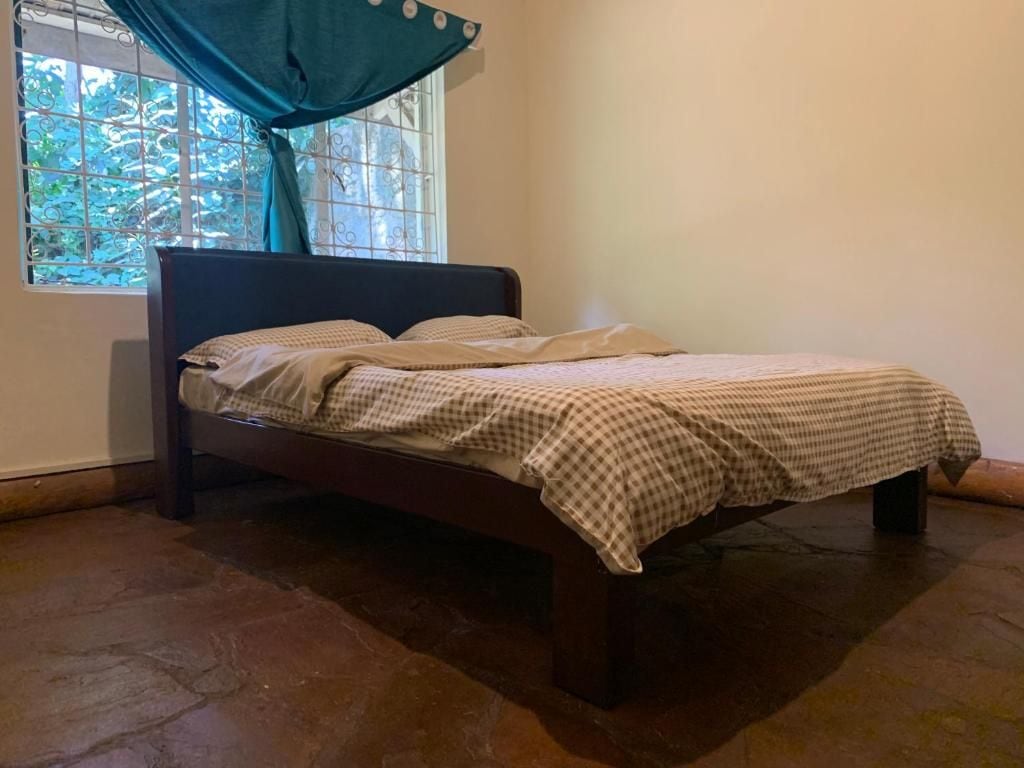 Een enkel bed met een geruit beddegoed in een kamer met raam en gordijn.
