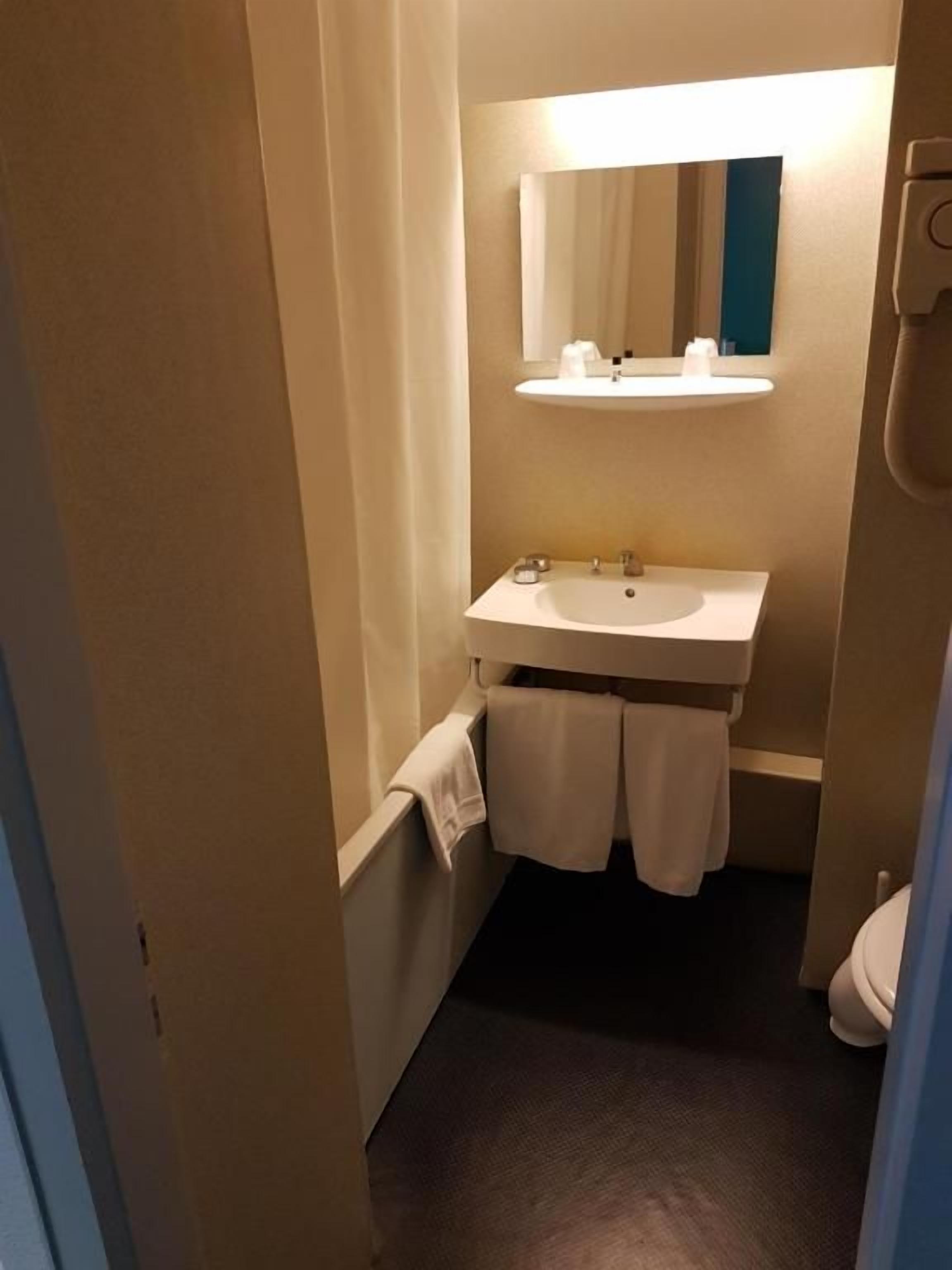 Ein kleines Badezimmer mit Waschbecken, Spiegel und Handtuchhalter.