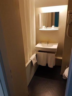 Un baño pequeño con lavamanos, espejo y toallero.