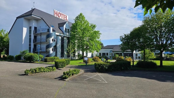 Un hotel con diseño moderno, estacionamiento y jardines bien cuidados.