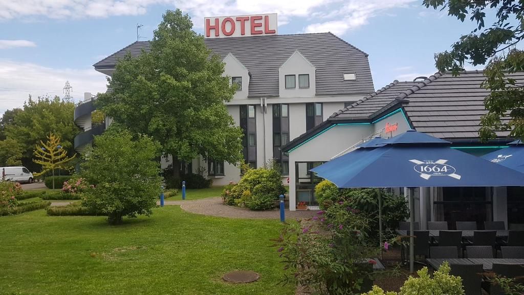Un hôtel avec une enseigne, une pelouse et des tables à l’extérieur.