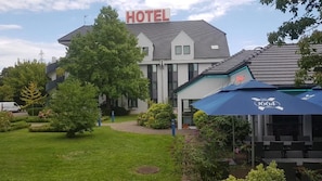 Un hotel con letrero, césped y asientos al aire libre.