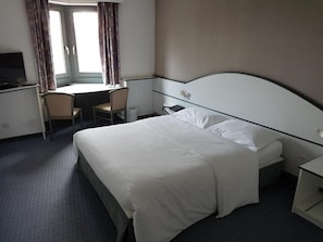 Una habitación de hotel con una cama, un escritorio, una silla y un televisor.