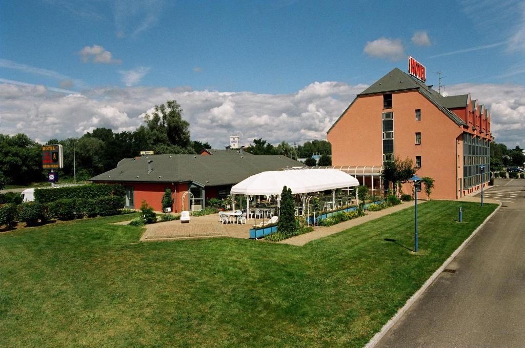 Ein Hotel mit einem roten Gebäude, einem weiß befesteten Bereich und blauem Himmel.
