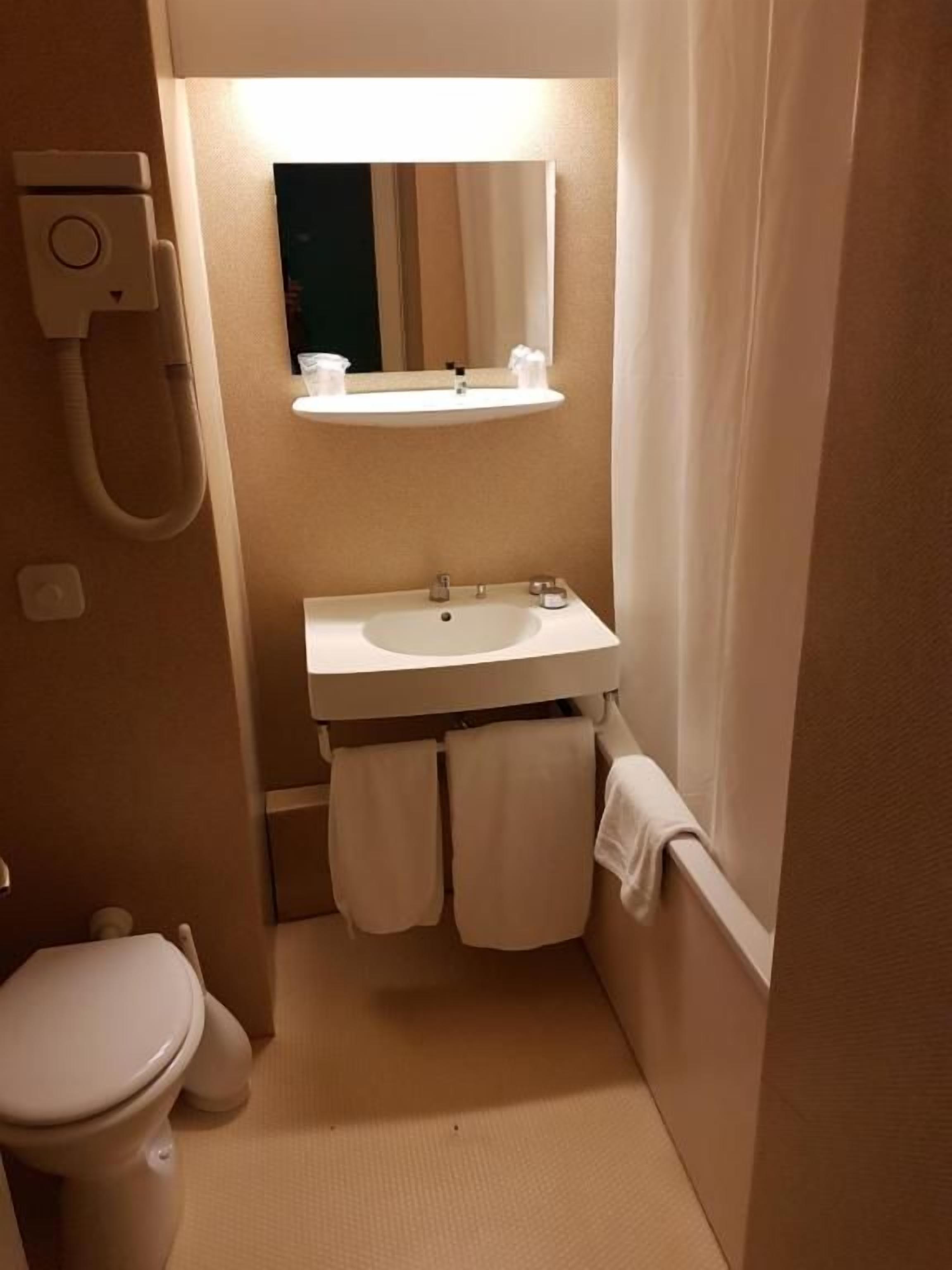 A small bathroom with a toilet, sink, and a mirror above the sink.
