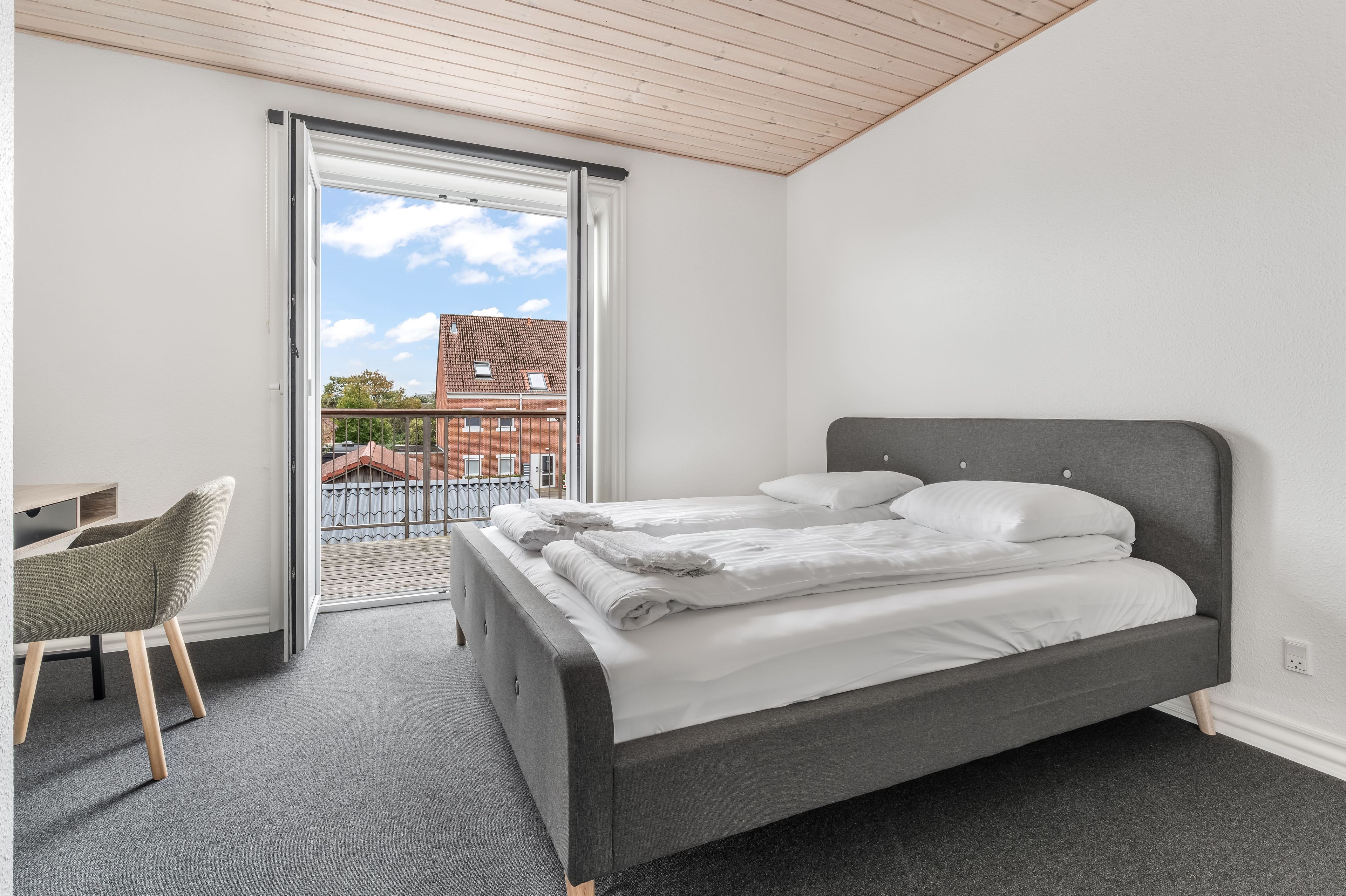 Quarto com cama, escrivaninha e cadeira.