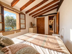 Ein Schlafzimmer mit einem großen Bett, Holzbalken, einem Schminktisch und Blick ins Freie.