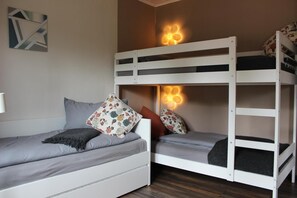 Une chambre avec un lit superposé, un bureau et une lampe.