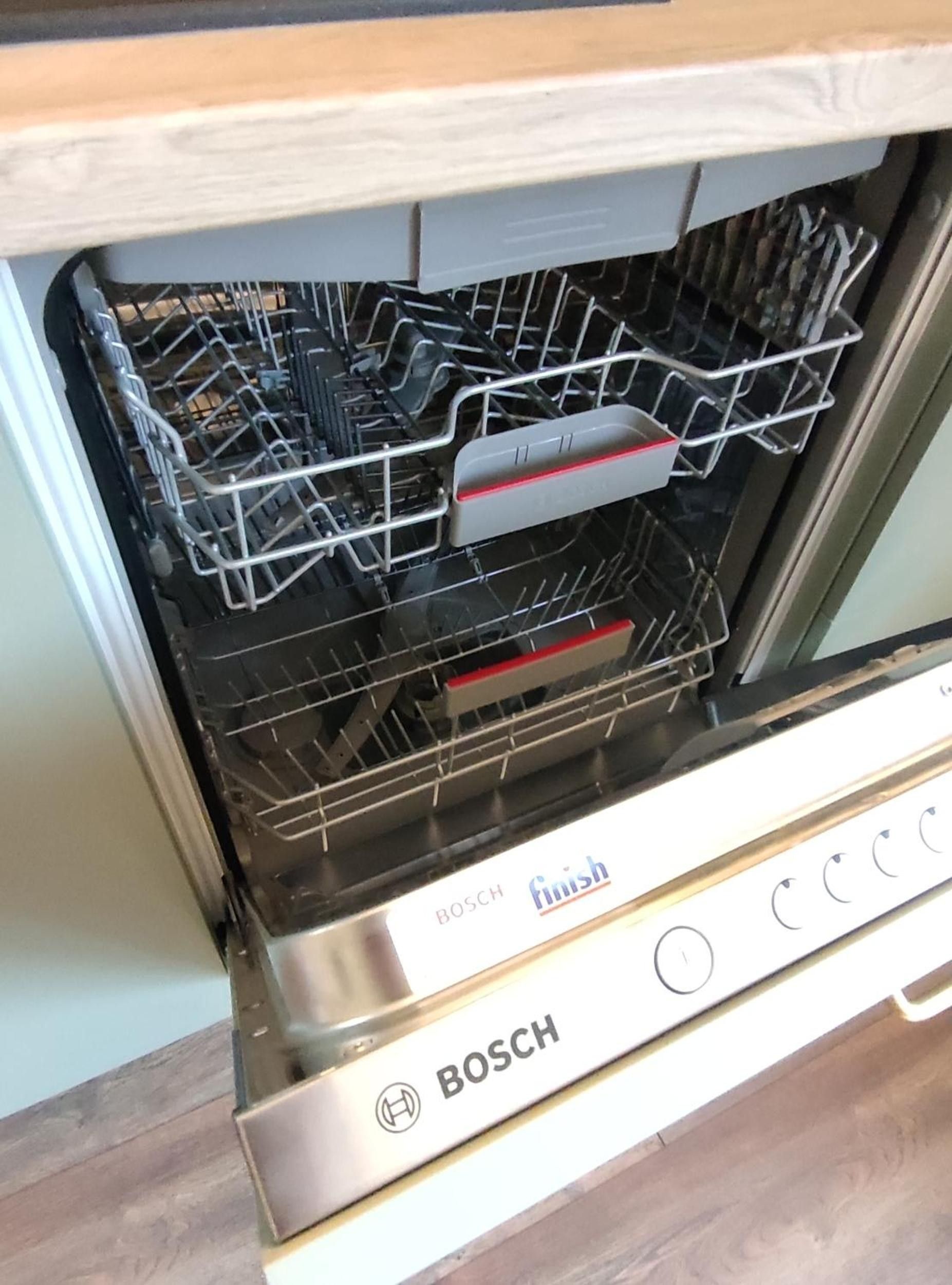 An open Bosch dishwasher with a stainless steel finish and a red control panel.
