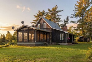 Une cabane en rondins dotée d’un grand porche vitré, d’une cheminée et d’antennes paraboliques.