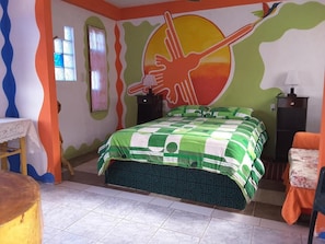 A bedroom with a bed, a nightstand, a chair, and a wall mural. - Hostal La Casa del Sol (Copacabana)