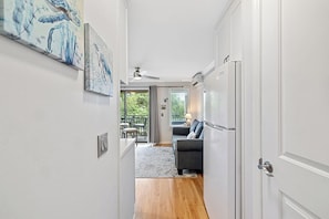 A hallway leading to a living area with a ceiling fan, a refrigerator, and a dining area with a table and chairs. - Coastal Charm – Ocean Views & Island Breezes! (HILTON HEAD ISLAND)