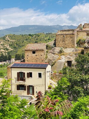 A building with a tiled roof, a balcony, and a view of a mountainous landscape.