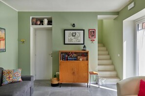 A living room with a sofa, a cabinet, a staircase, and a door.