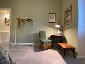 Une pièce dotée d’un coin salon comprenant une chaise, un banc et une petite table avec une lampe.