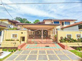 A residential property with a gated entrance, a covered porch, and a paved driveway.