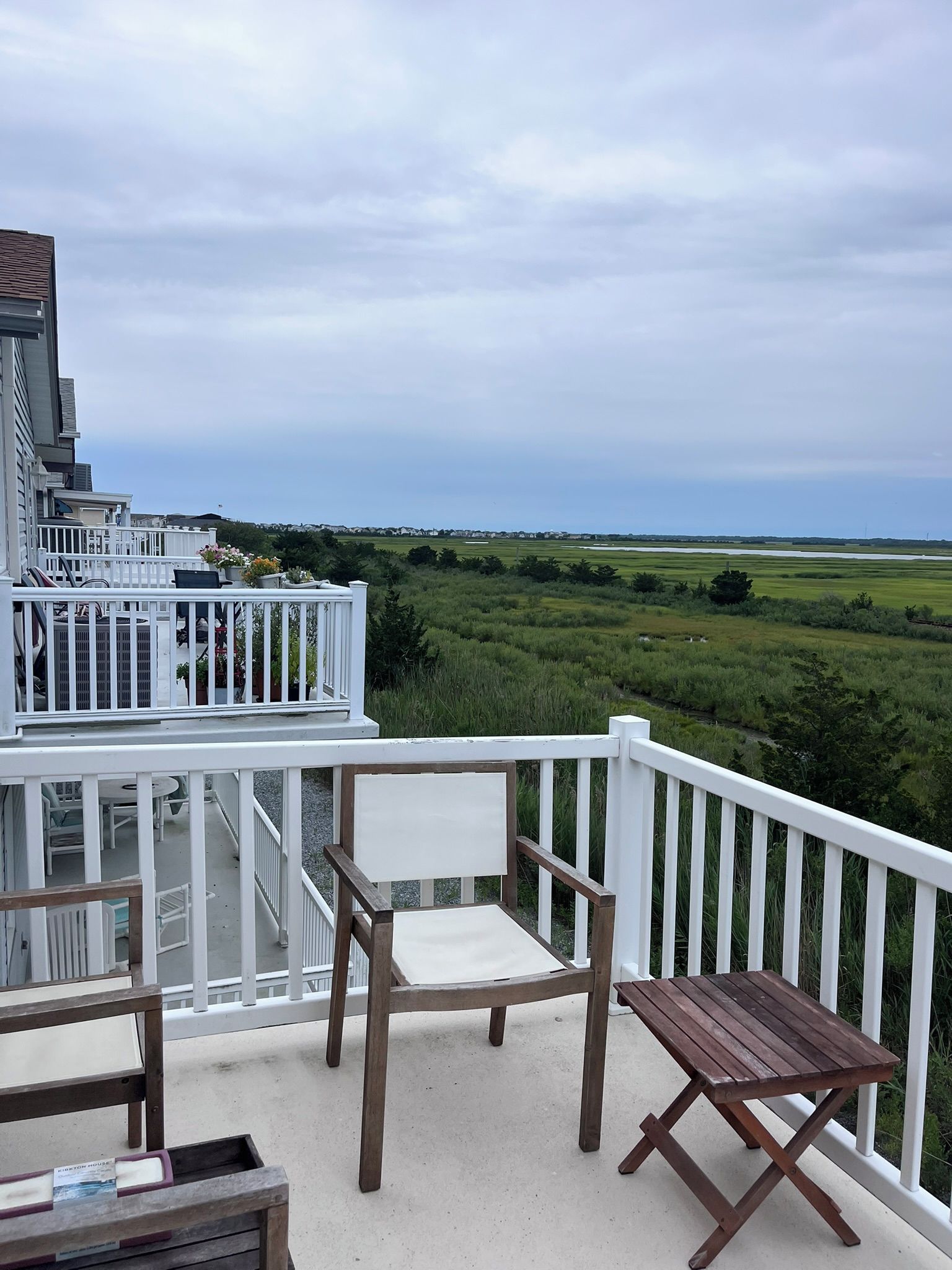 Un balcon donnant sur un champ verdoyant et un ciel nuageux.