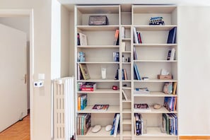A white bookshelf with various books, a radio, and a toy bus. - Seafront Apartment | Panoramic Sea Views | Thessaloniki Center (Thessaloniki)