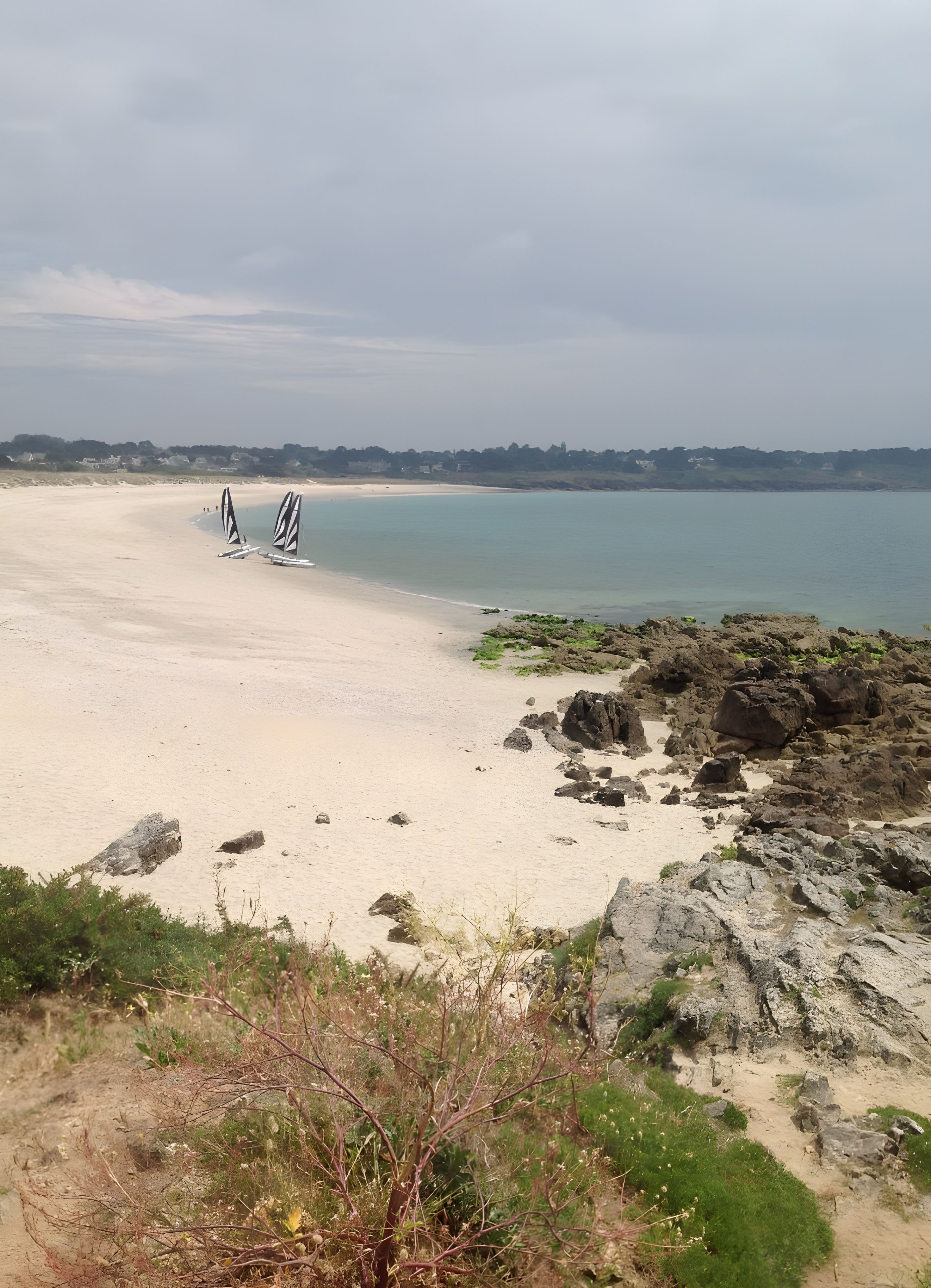Una spiaggia con una riva sabbiosa, una zona rocciosa e un cielo sereno.