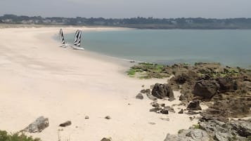 Una spiaggia con una riva sabbiosa, una zona rocciosa e un cielo sereno.