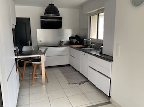 A modern kitchen with white cabinetry, a black countertop, and a window. - Holiday Home 'Gite Les Hauts Du Goh-Vras' with Private Pool, Private Terrace and Wi-Fi (Saint-Gildas-de-Rhuys)