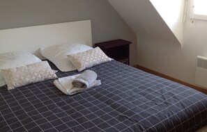 A neatly made bed with a dark checkered bedspread and multiple pillows, including a rolled towel. - Holiday Home 'Gite Les Hauts Du Goh-Vras' with Private Pool, Private Terrace and Wi-Fi (Saint-Gildas-de-Rhuys)