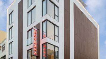 Un hôtel moderne, doté d’une enseigne verticale bien visible, de grandes fenêtres et d’une façade soignée.