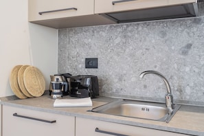 A kitchen with a stainless steel sink, a coffee maker, and a toaster on the countertop. - Close To Everything Apts (Como)
