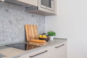A kitchen with a marble backsplash, a wooden cutting board, a loaf of bread, a bowl of lemons, and a potted plant. - Close to Everything 1 by Rent All Como (Como)