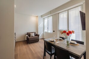 En matplats med ett bord dukat för två personer, en soffa och ett fönster med gardiner.