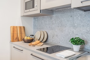 A kitchen with a microwave, a bread loaf, a bowl of fruit, a cutting board, and a potted plant. - Close To Everything 3 by Rent All Como (Como)