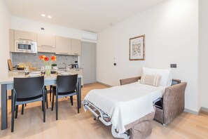 Une chambre d’hôtel compacte comprenant un coin cuisine, un espace repas et un lit avec une tête de lit.