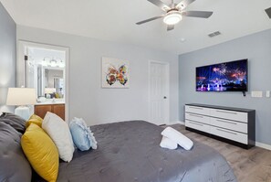 A bedroom with a bed, a ceiling fan, a television, and a door. - Epic Providence Family Escape (Davenport)