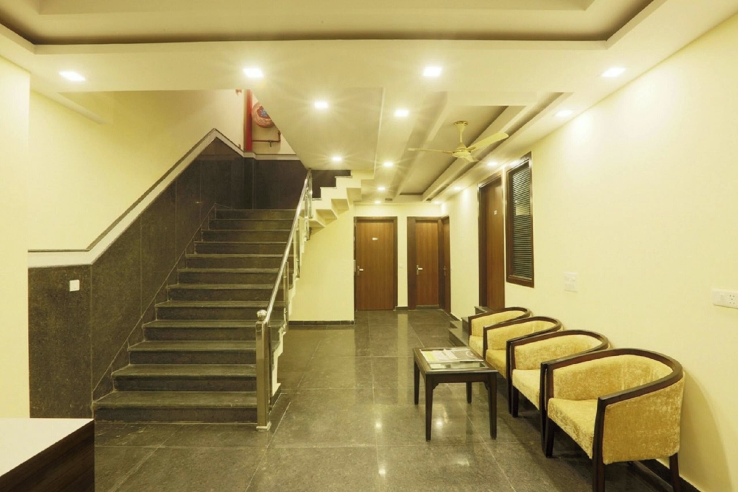 Eine Hotelhalle mit Treppe, einer Rezeption und einer Sitzgelegenheit.