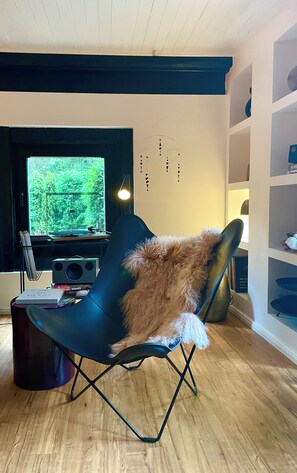 Un salon moderne avec un fauteuil noir, un téléviseur et une bibliothèque.